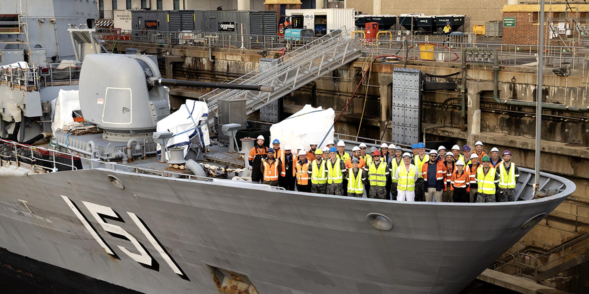 Large Royal Australian Navy ship, with shipbuilders on the prow